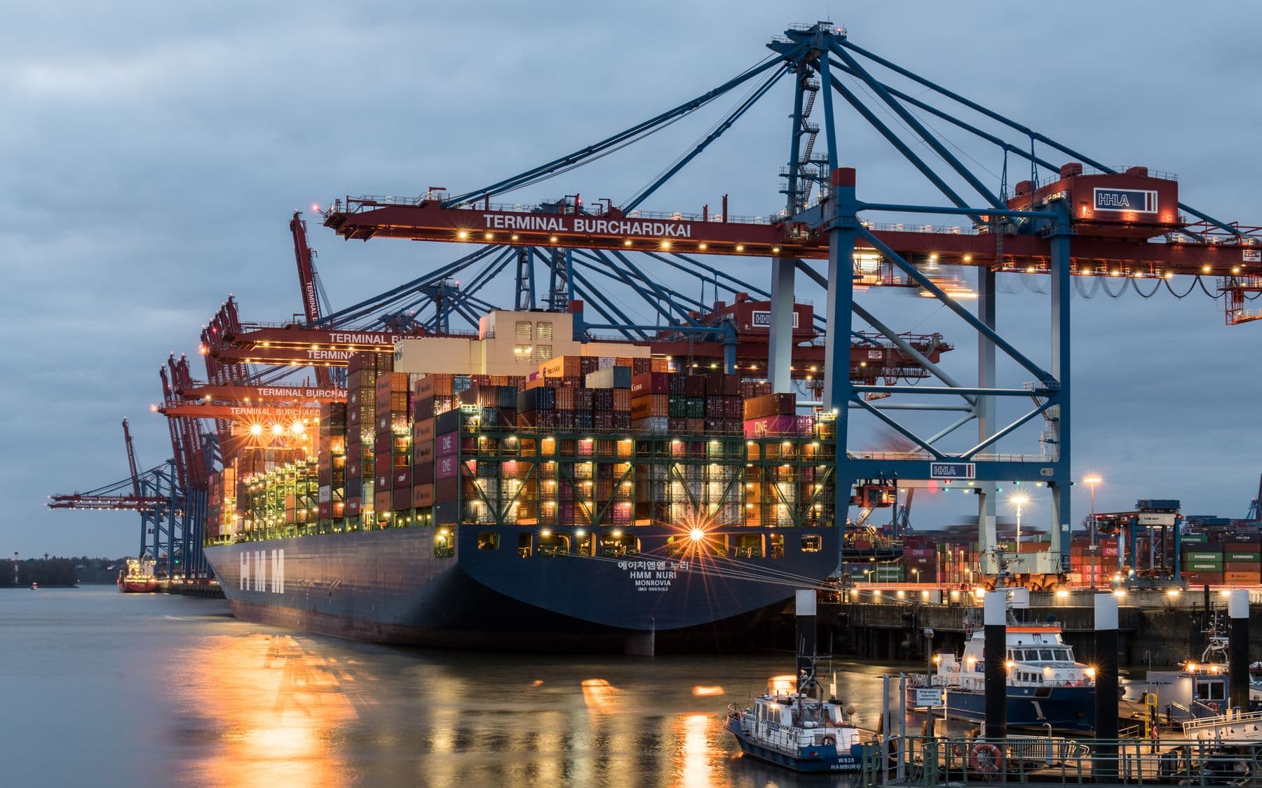 Container terminal at dusk with gantry cranes loading a cargo vessel